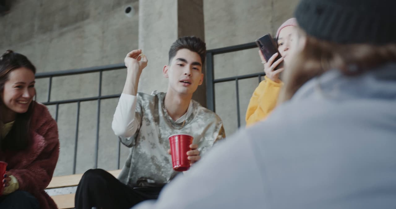 Friends hanging out on concrete steps, laughing and checking their phones